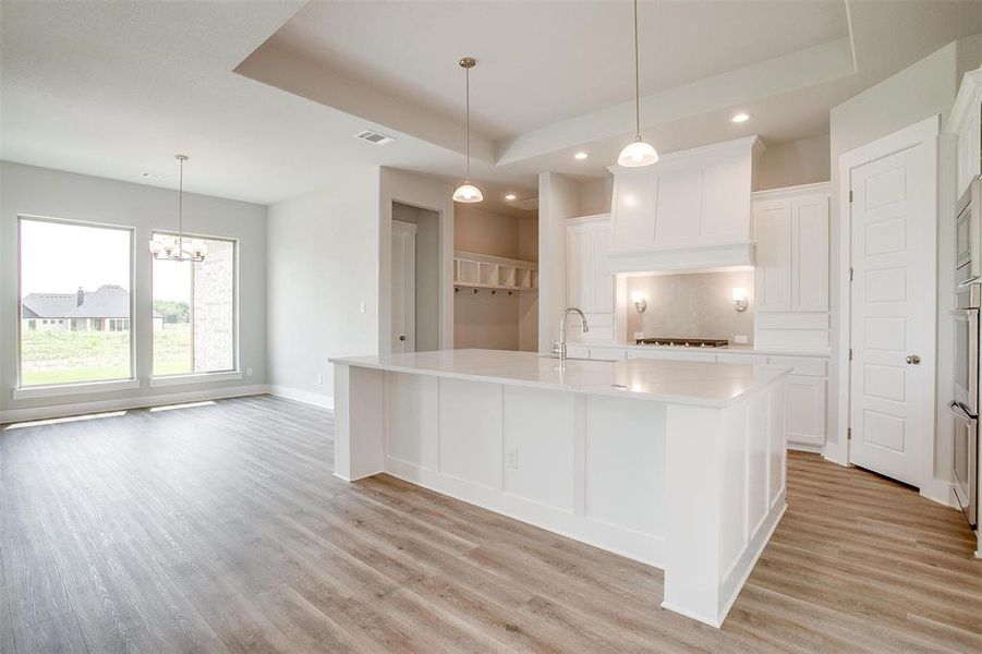 Kitchen with a large island with sink, white cabinets, and light wood-type flooring