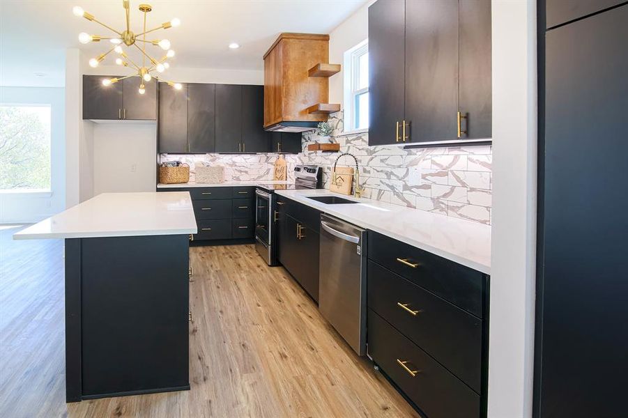 Kitchen featuring hanging light fixtures, sink, a kitchen island, backsplash, and appliances with stainless steel finishes