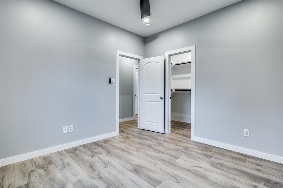 Unfurnished bedroom featuring a walk in closet, light hardwood / wood-style flooring, and a closet