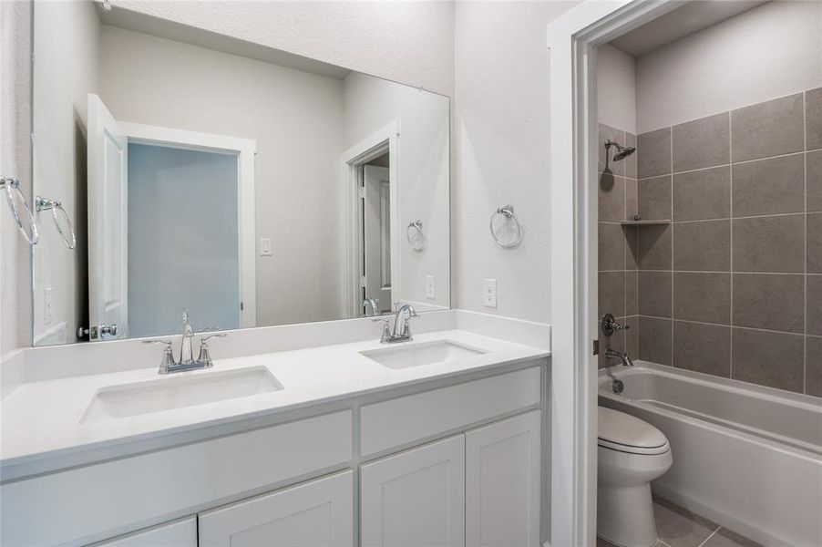 Full bathroom with tile patterned flooring, tiled shower / bath, vanity, and toilet