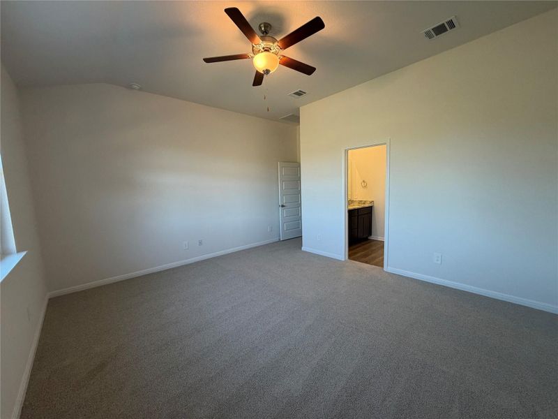 Unfurnished bedroom with carpet, ceiling fan, ensuite bath, and vaulted ceiling