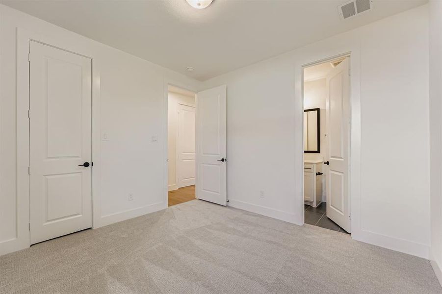 Unfurnished bedroom with light carpet and ensuite bathroom