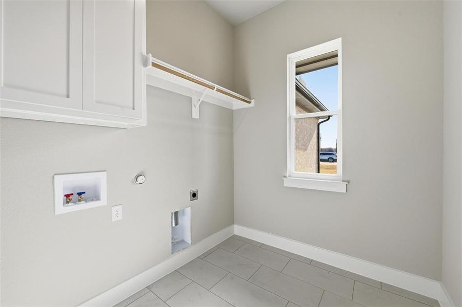 Laundry area featuring hookup for a washing machine, electric dryer hookup, gas dryer hookup, cabinet space, and light tile patterned floors