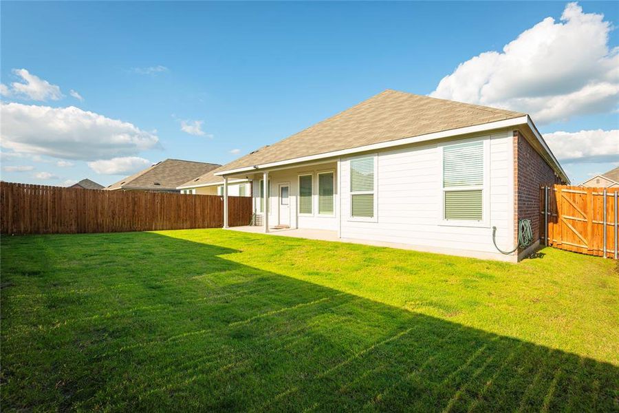 Expansive backyard with a manicured lawn, full privacy fencing, and a covered patio Expansive backyard with a manicured lawn, full privacy fencing, and a covered patio