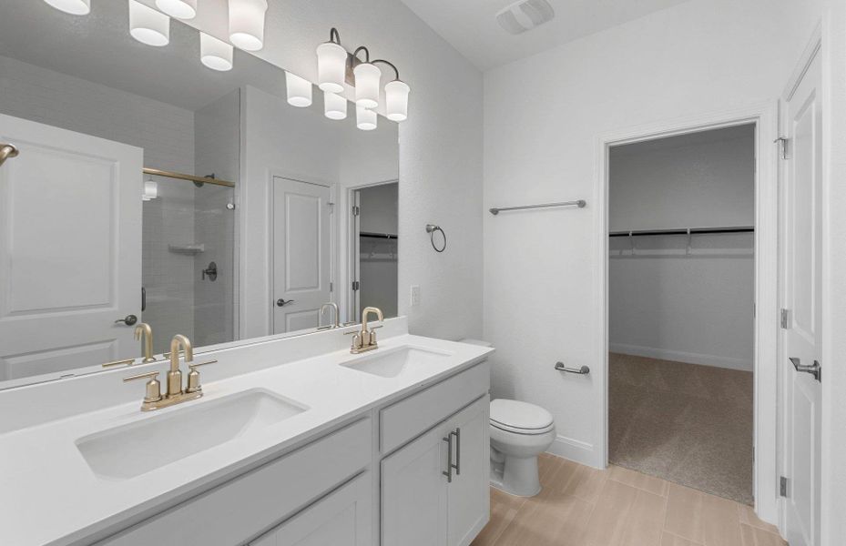 Full bathroom with a walk in closet, a stall shower, double vanity, light tile patterned floors, and light colored carpet
