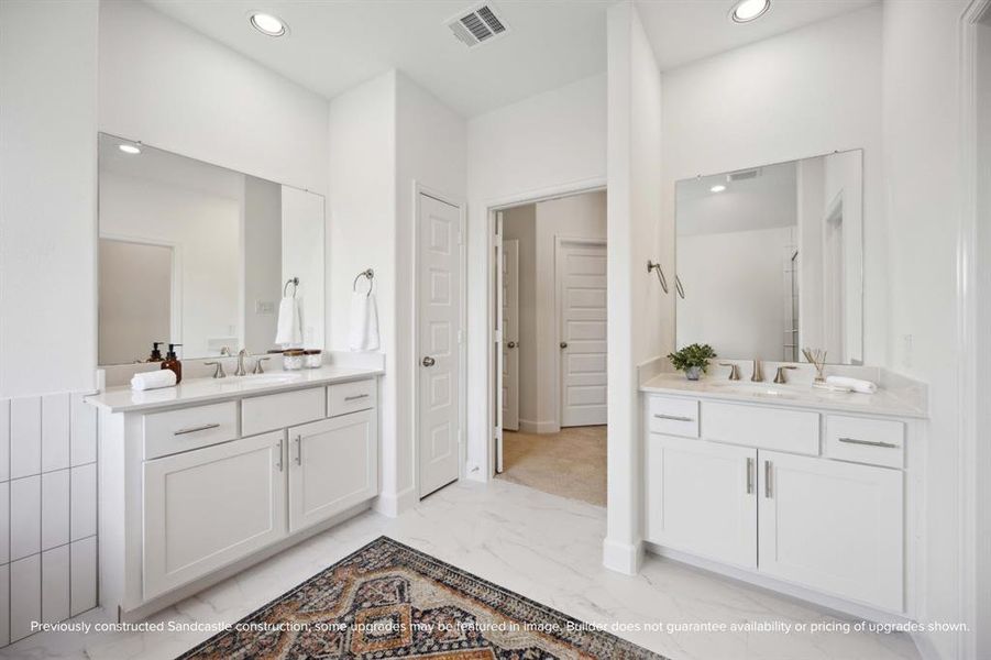 Spa-like Splendor: Dual vanities, a roomy linen closet, and a secluded water closet are set amid abundant space for an everyday spa experience right at home.