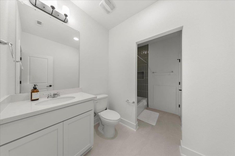 Bathroom with vanity, washtub / shower combination, and light tile patterned floors Bathroom with vanity, washtub / shower combination, and light tile patterned floors