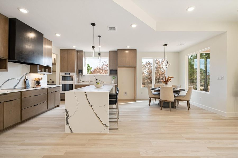 Kitchen with hanging light fixtures, a kitchen bar, modern cabinets, a kitchen island, and recessed lighting