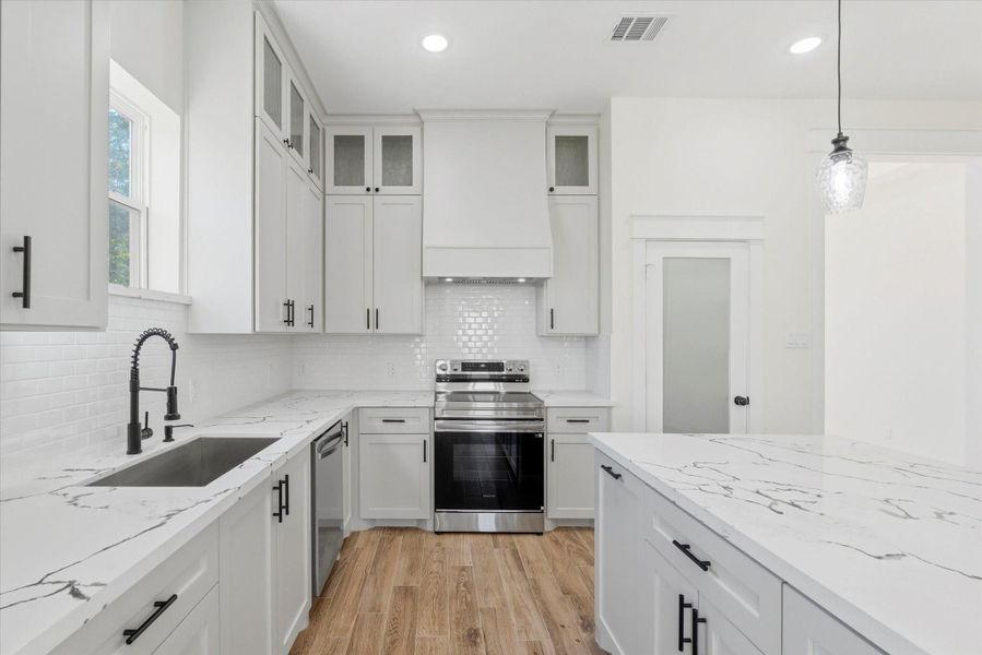 Custom solid wood cabinetry, a unique island with additional seating, and floor-to-ceiling cabinets accented with decorative glass fronts add an elegant, elevated touch. Custom solid wood cabinetry, a unique island with additional seating, and floor-to-ceiling cabinets accented with decorative glass fronts add an elegant, elevated touch.