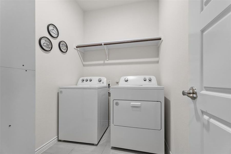 Laundry room with washer and clothes dryer and light tile patterned floors Laundry room with washer and clothes dryer and light tile patterned floors