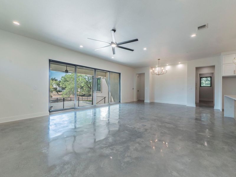 Unfurnished room featuring recessed lighting, concrete floors, a ceiling fan, and a chandelier Unfurnished room featuring recessed lighting, concrete floors, a ceiling fan, and a chandelier