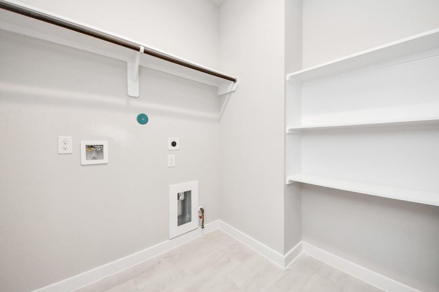 A perfect blend of functionality and comfort. Capture the essence of easy living with a first-floor laundry room, thoughtfully equipped with shelving for effortless organization. Both electric and gas connections available. Sample photo of completed home with similar floor plan. Actual colors and selections may vary.
