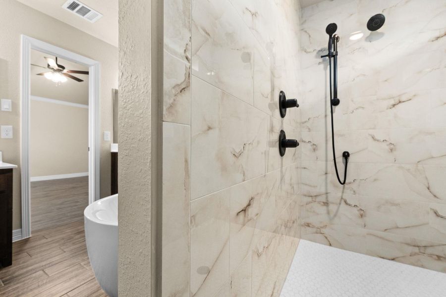 Full bathroom featuring double vanities, a marble finish walk-in shower, a freestanding bath, and wood like tile floors Full bathroom featuring double vanities, a marble finish walk-in shower, a freestanding bath, and wood like tile floors