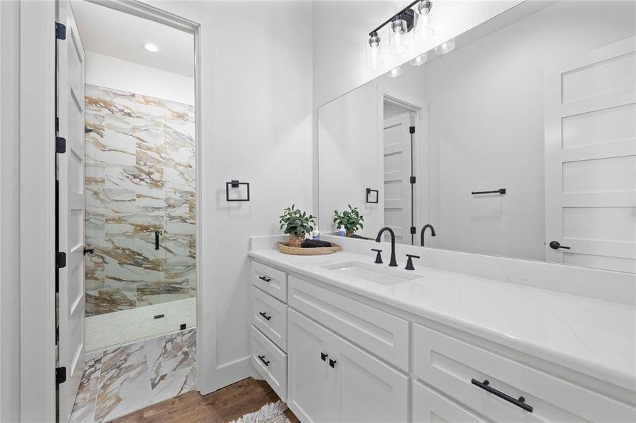 Full bath with a stall shower, vanity, dark marble finish flooring, and recessed lighting