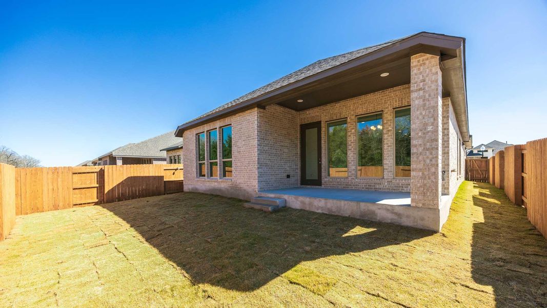 Back of house featuring a patio, a fenced backyard, and brick siding