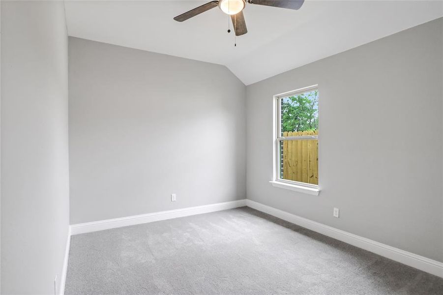 Carpeted spare room with vaulted ceiling and ceiling fan