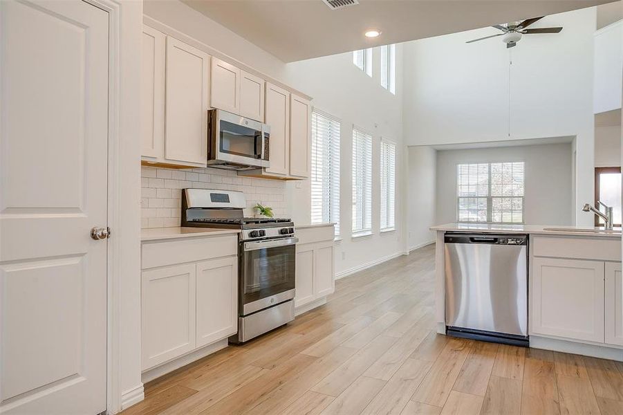 Kitchen featuring white cabinets, sink, light hardwood / wood-style flooring, ceiling fan, and stainless steel appliances