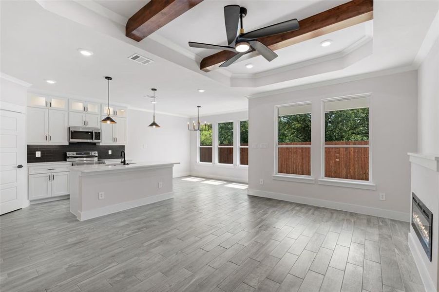 Kitchen featuring light wood-type flooring, ceiling fan with notable chandelier, stainless steel appliances, sink, and white cabinets