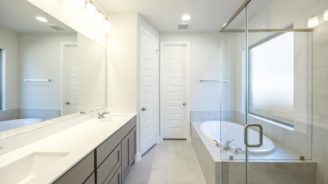 Bathroom featuring double vanity, a stall shower, a bath, recessed lighting, and light tile patterned floors Bathroom featuring double vanity, a stall shower, a bath, recessed lighting, and light tile patterned floors