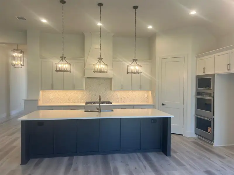 Kitchen with 10-ft island, 36" gas cooktop, double-oven, and built-in microwave