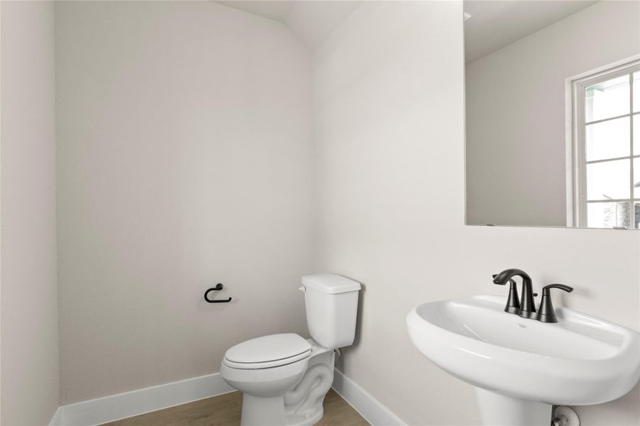 Half bathroom featuring toilet, wood finished floors, baseboards, and a sink Half bathroom featuring toilet, wood finished floors, baseboards, and a sink