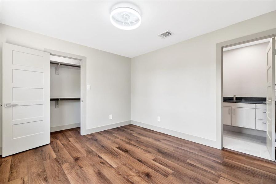 Unfurnished bedroom with dark wood-style flooring and ensuite bath Unfurnished bedroom with dark wood-style flooring and ensuite bath