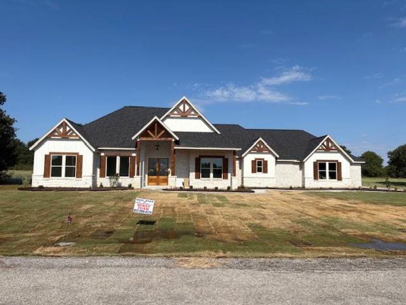 Modern farmhouse style home featuring covered porch and a front lawn