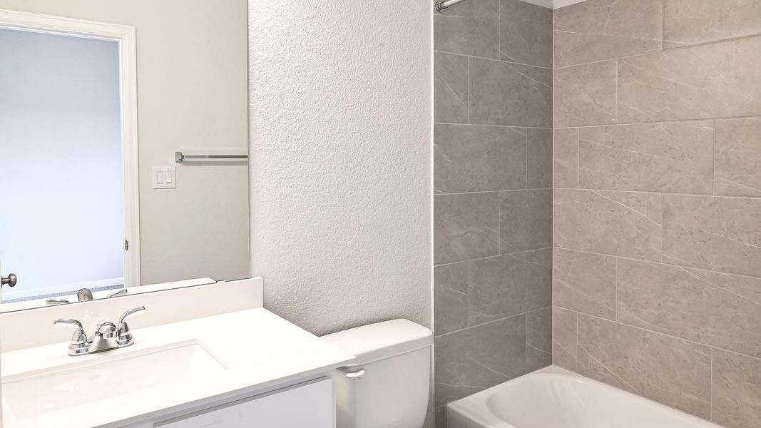 Bathroom featuring a textured wall, vanity, and bathtub / shower combination Bathroom featuring a textured wall, vanity, and bathtub / shower combination