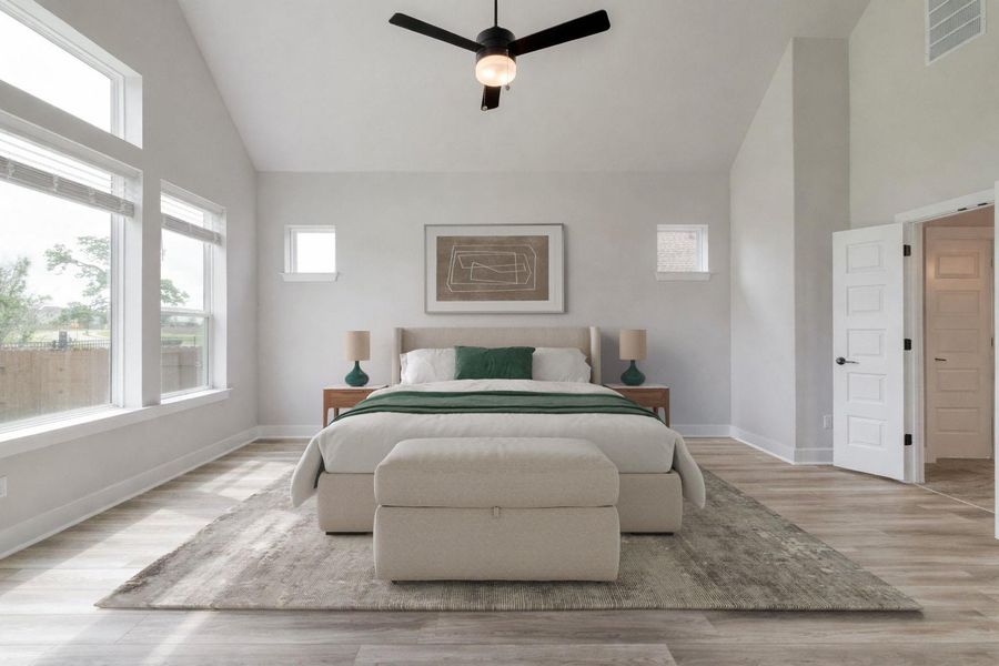 Spacious room featuring vaulted ceilings, wood-finish flooring, a contemporary ceiling fan, and multiple windows providing natural illumination