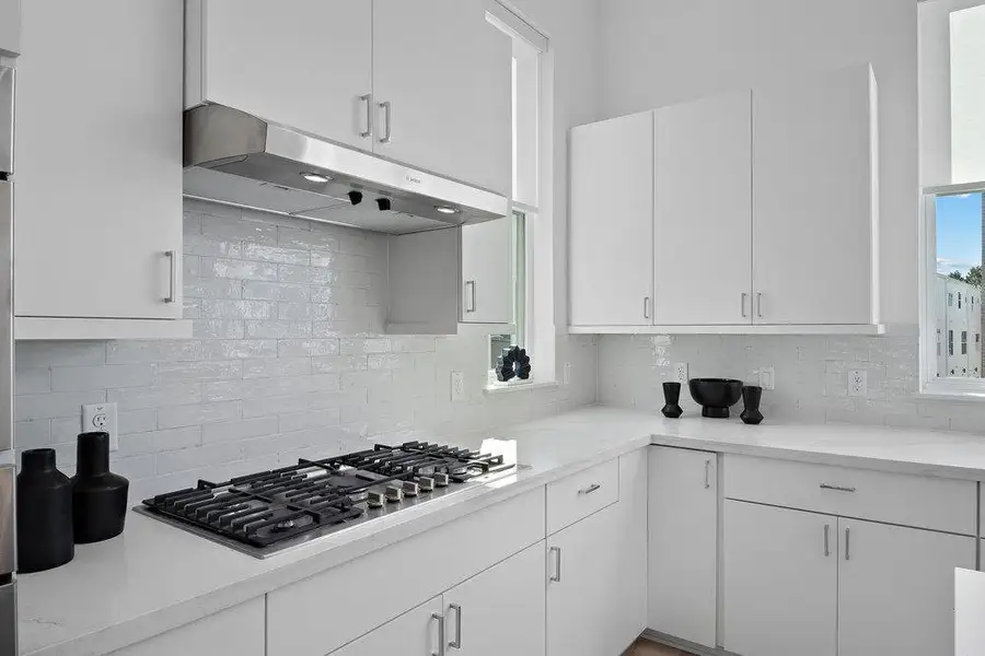 Kitchen with white cabinetry, stainless steel gas cooktop, and decorative backsplash Kitchen with white cabinetry, stainless steel gas cooktop, and decorative backsplash