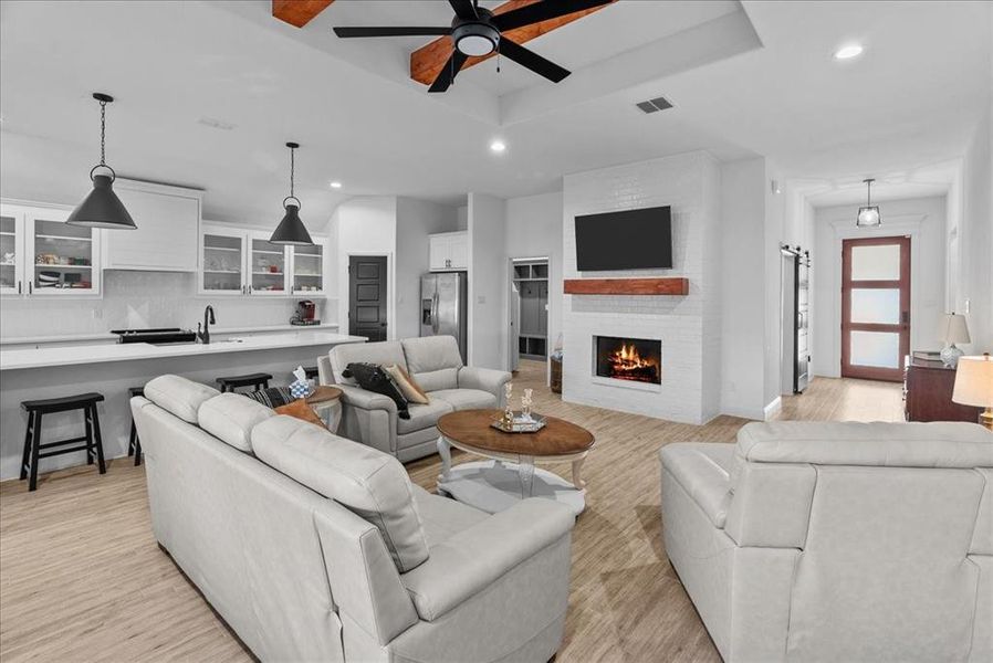 Living room with light wood-style floors, recessed lighting, a raised ceiling, and ceiling fan