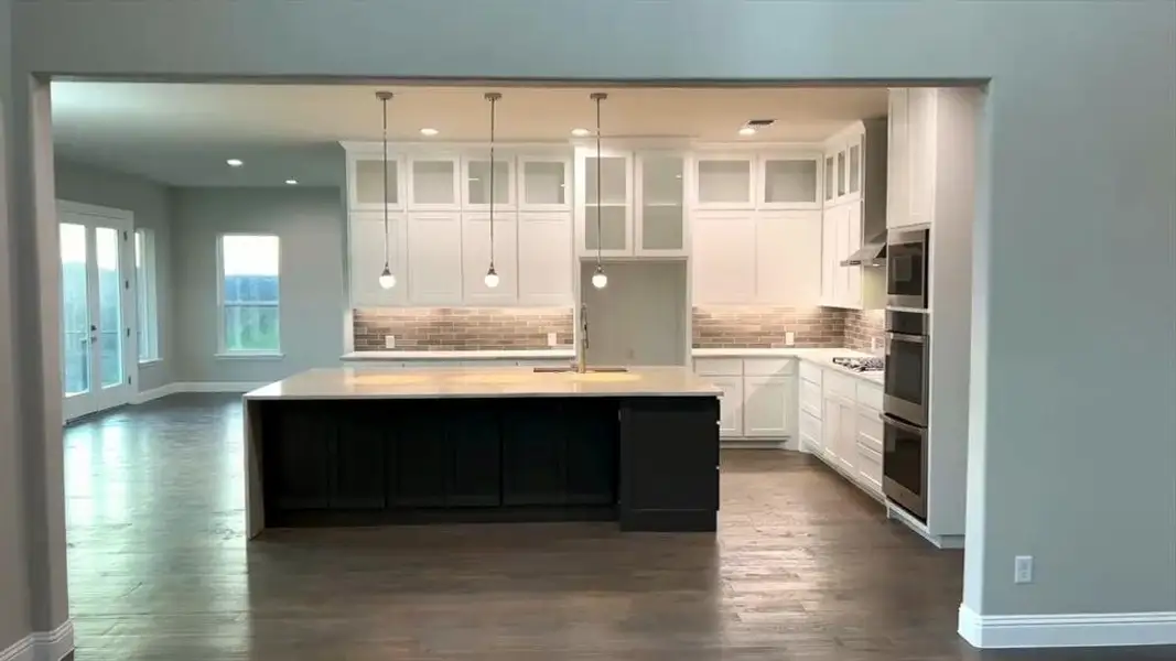 Kitchen with white cabinetry, decorative backsplash, recessed lighting, an island with sink, and dark wood finished floors