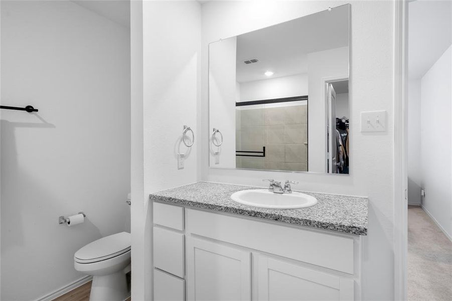 Bathroom vanity featuring a speckled countertop, integrated sink with chrome faucet, and white cabinet storage Bathroom vanity featuring a speckled countertop, integrated sink with chrome faucet, and white cabinet storage