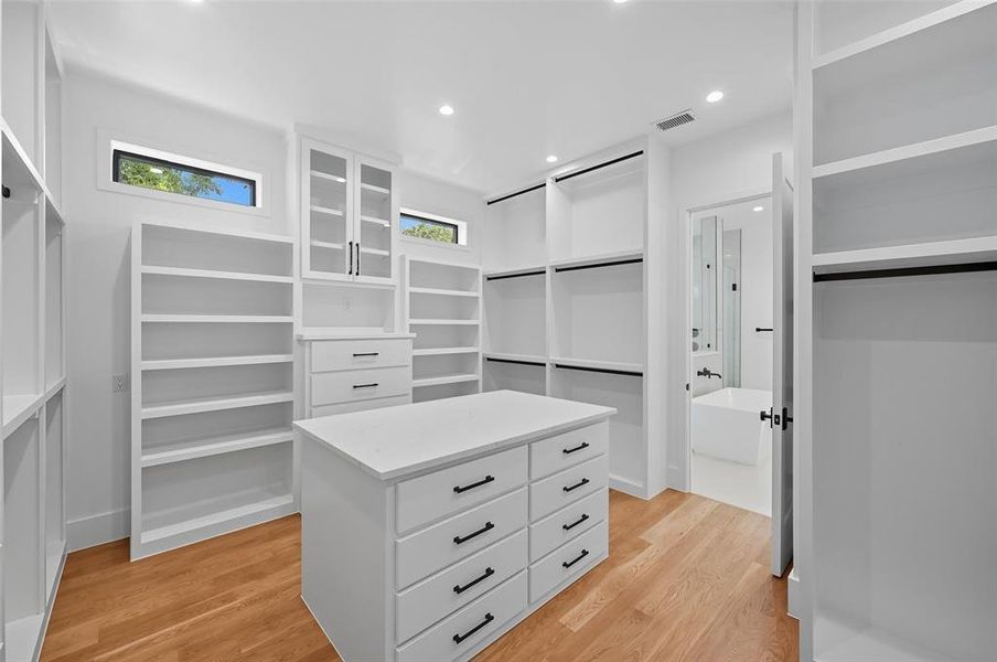 Example Expansive custom closet featuring extensive white built-in shelving, a central island with drawer storage, and warm wood-finish flooring Example Expansive custom closet featuring extensive white built-in shelving, a central island with drawer storage, and warm wood-finish flooring