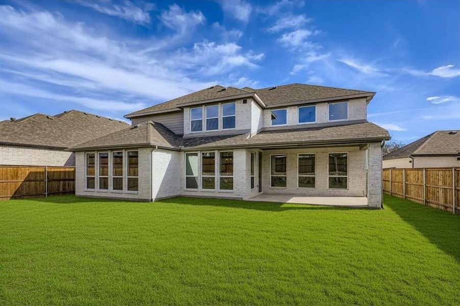 Back of property with brick siding, a fenced backyard, a patio, and roof with shingles
