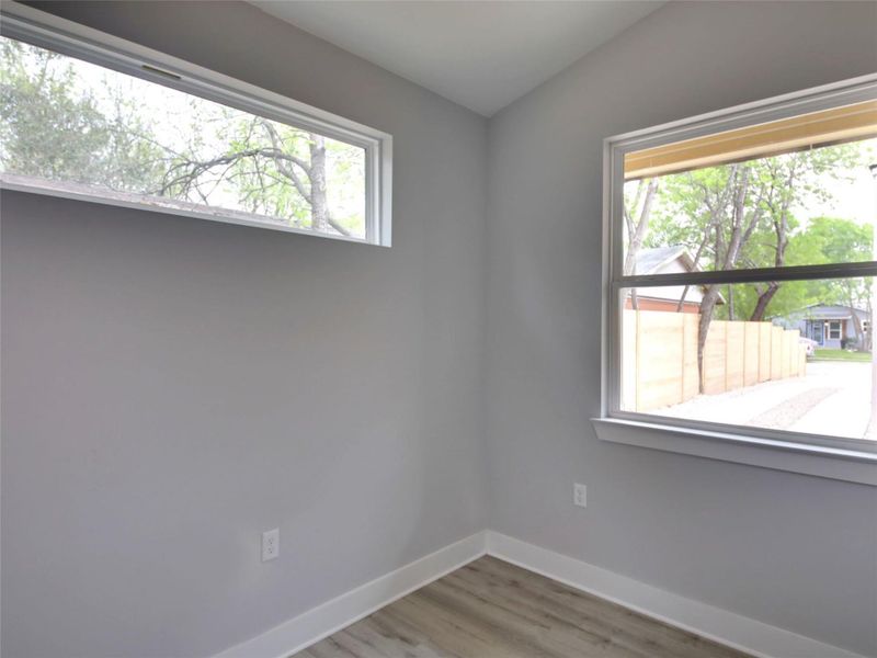 Unfurnished room with plenty of natural light, light wood finished floors, and lofted ceiling