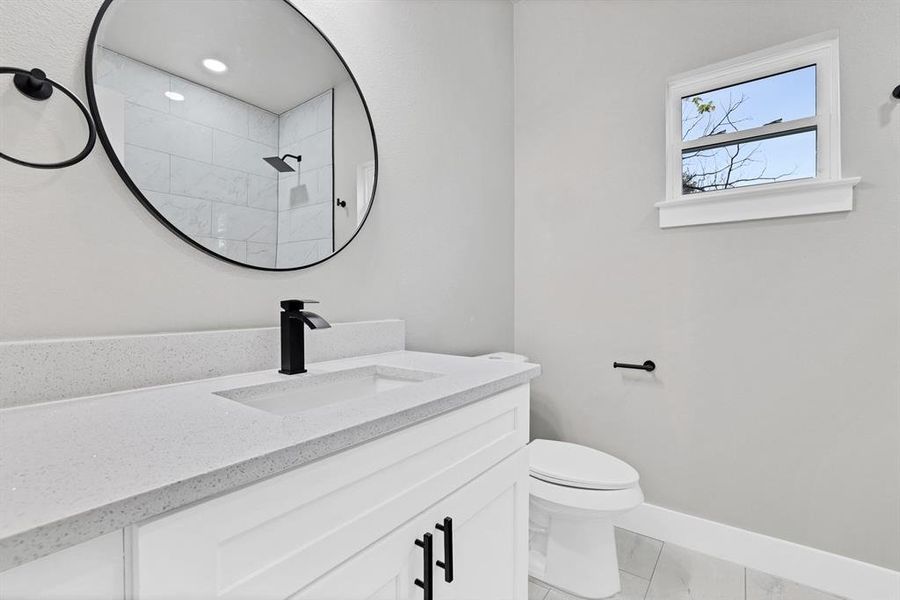 Bathroom featuring a tile shower, vanity, toilet, and tile patterned floors