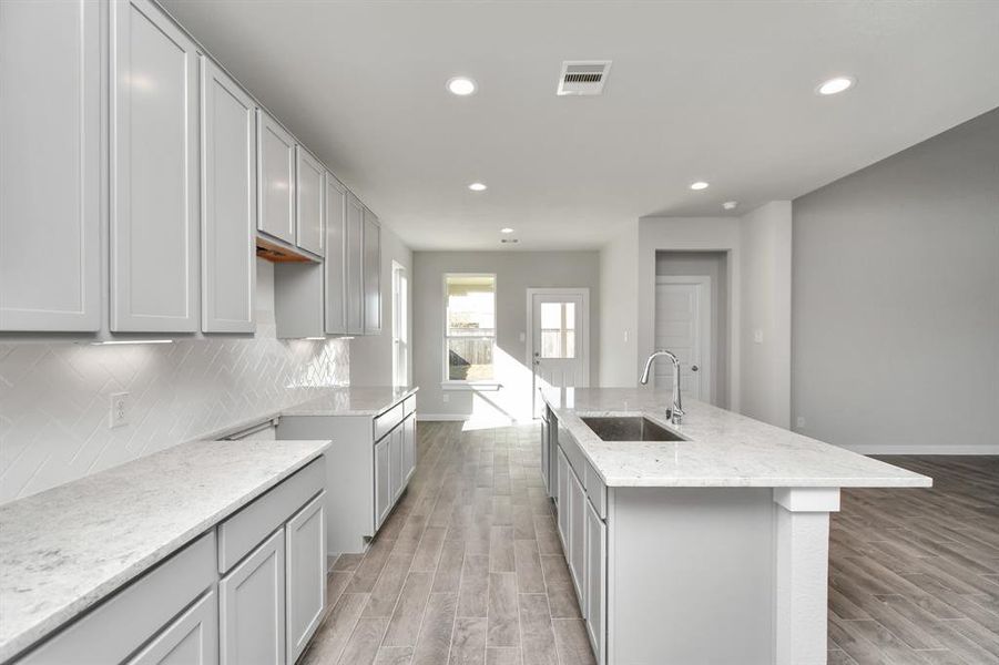 Discover another perspective of this stunning kitchen, generously appointed with an abundance of counter space. Sample photo of completed home with similar floor plan. As-built interior colors and selections may vary.