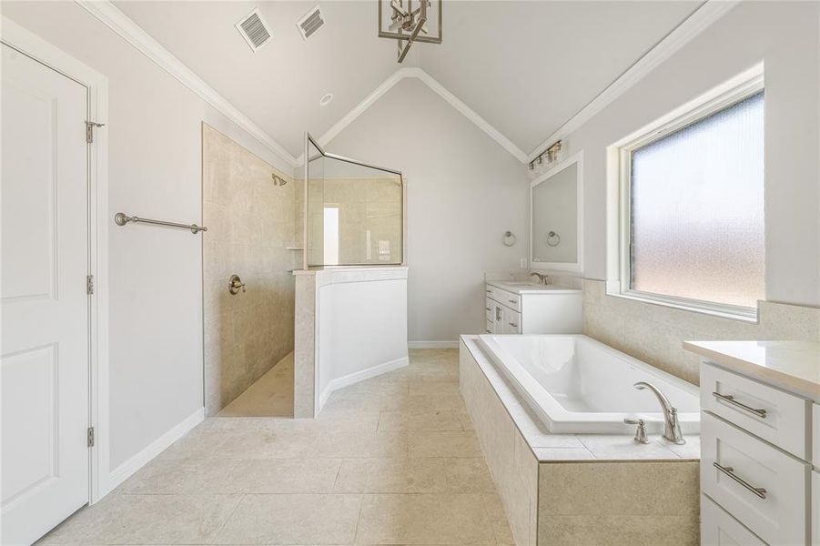 Bathroom featuring vanity, a bath, ornamental molding, a walk in shower, and vaulted ceiling Bathroom featuring vanity, a bath, ornamental molding, a walk in shower, and vaulted ceiling