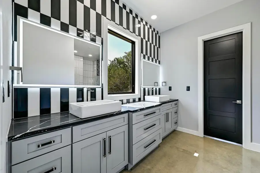 Enjoy a custom crafted, deluxe primary ensuite bathroom complete with a spacious dual vanity, unique designer backsplash, lit mirrors, and a window with views. Enjoy a custom crafted, deluxe primary ensuite bathroom complete with a spacious dual vanity, unique designer backsplash, lit mirrors, and a window with views.