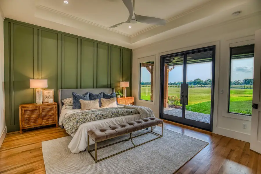Bedroom featuring access to outside, ornamental molding, light wood-style flooring, ceiling fan, and a tray ceiling Bedroom featuring access to outside, ornamental molding, light wood-style flooring, ceiling fan, and a tray ceiling