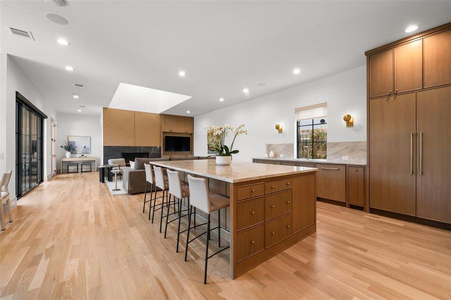 Kitchen with a kitchen breakfast bar, a tile fireplace, a large island, wood finish cabinets, and recessed lighting