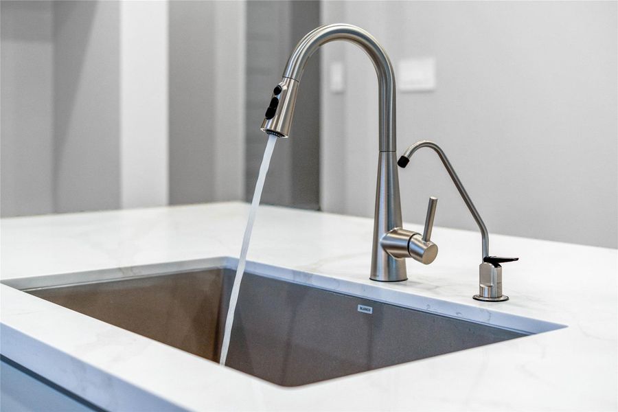 The Moen Sleek stainless steel kitchen faucet offers versatility and contemporary design, complemented by a convenient separate filtered water dispenser faucet.