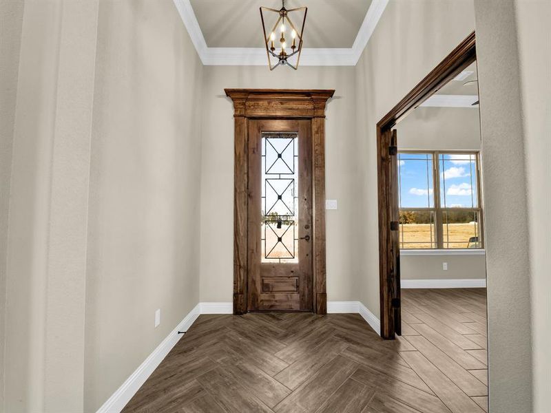 Foyer with a notable chandelier, parquet flooring, and crown molding