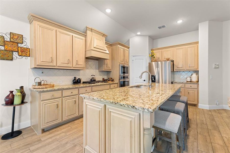 Kitchen featuring light stone counters, decorative backsplash, light wood-type flooring, appliances with stainless steel finishes, and recessed lighting Kitchen featuring light stone counters, decorative backsplash, light wood-type flooring, appliances with stainless steel finishes, and recessed lighting