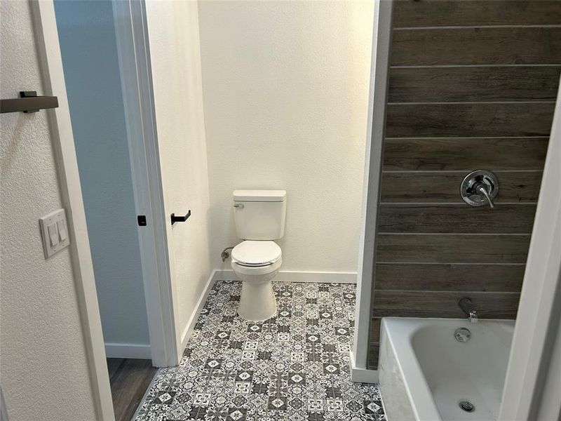 Full bath with a textured wall and washtub / shower combination Full bath with a textured wall and washtub / shower combination