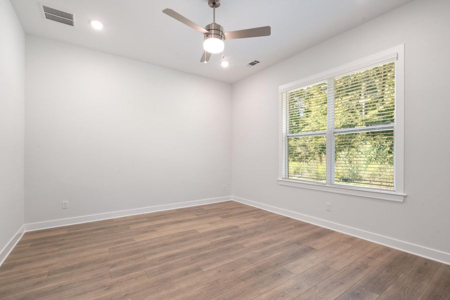 Wood-finish flooring, recessed lighting, ceiling fan with integrated light, and a large window with blinds