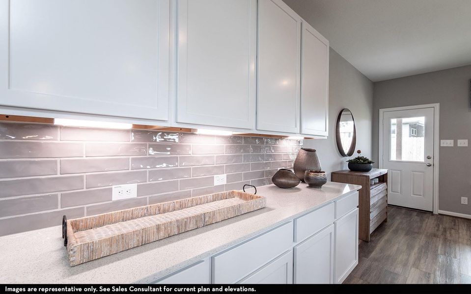 Kitchen with white cabinets, tasteful backsplash, dark wood-style flooring, and light stone counters