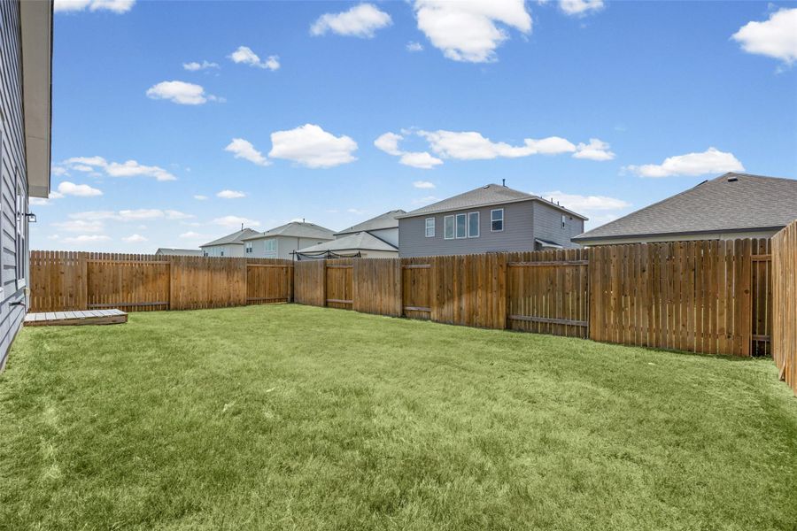 A spacious green lawn is fully enclosed by a sturdy wooden privacy fence. A spacious green lawn is fully enclosed by a sturdy wooden privacy fence.