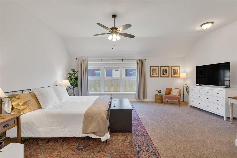 Carpeted bedroom with ceiling fan and lofted ceiling